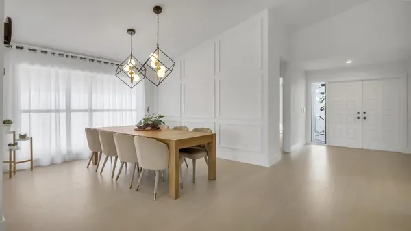 a dining room with wooden floor a chandelier a wooden table and chairs