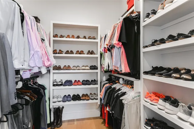 a view of walk in closet with clothes and shoes