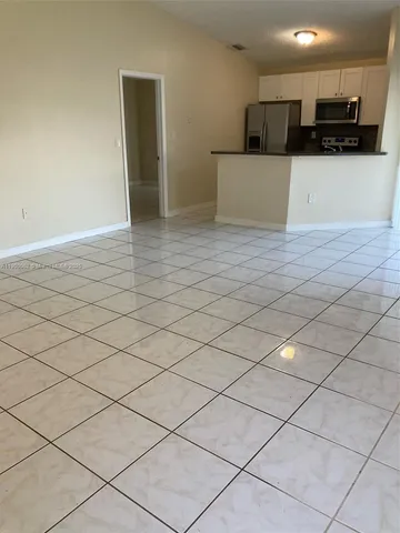 a view of kitchen with stainless steel appliances granite countertop a refrigerator and a stove top oven