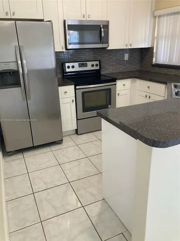 a kitchen with granite countertop a refrigerator and a stove top oven