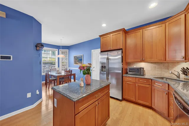 a kitchen with stainless steel appliances granite countertop a refrigerator a sink dishwasher a stove and white countertops with wooden floor