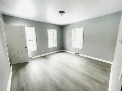 an empty room with wooden floor and windows