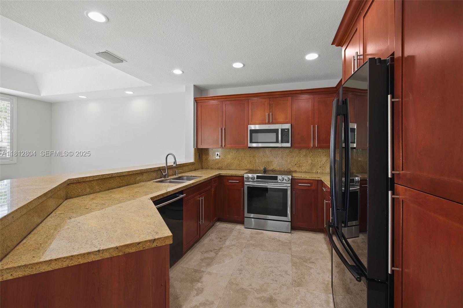 32360 Southwest 204th Avenue Homestead, FL 33030 - Photo 11 of 44 a kitchen with stainless steel appliances granite countertop sink stove and refrigerator