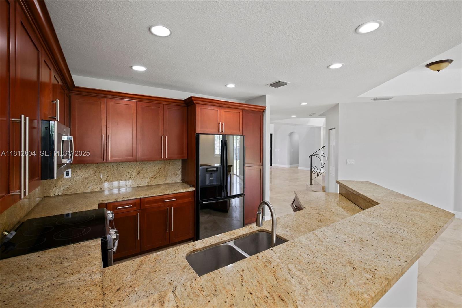 32360 Southwest 204th Avenue Homestead, FL 33030 - Photo 16 of 44 a kitchen with stainless steel appliances granite countertop a sink refrigerator and cabinets