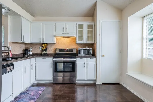 a kitchen with granite countertop a stove and white cabinets