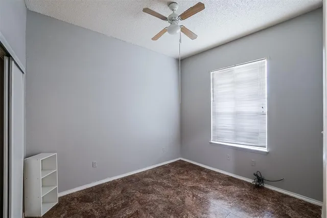an empty room with a window and a fan