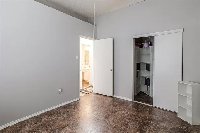 a view of an empty room with closet and a window