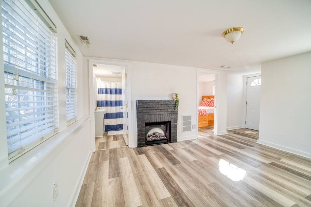 94 Sea Street, Unit B Barnstable, MA 02601 - Photo 6 of 6 a view of an empty room with wooden floor fireplace and a window