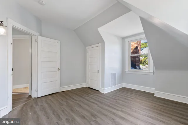 an empty room with wooden floor and window