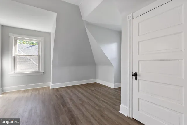 an empty room with wooden floor closet and windows