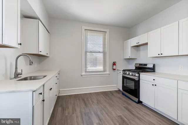 a kitchen with stainless steel appliances granite countertop white cabinets stove top oven and sink