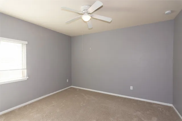 an empty room with a window and a fan