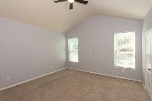 an empty room with windows and fan