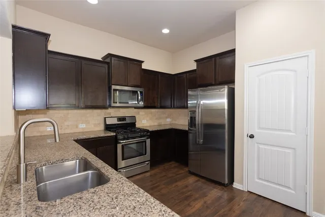 a kitchen with stainless steel appliances granite countertop a refrigerator a stove a sink and a microwave