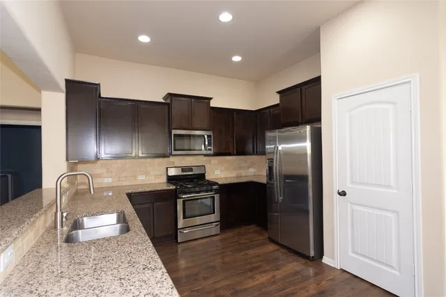 a kitchen with stainless steel appliances granite countertop a refrigerator sink and stove