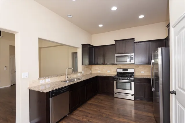 a kitchen with stainless steel appliances granite countertop a sink stove and refrigerator
