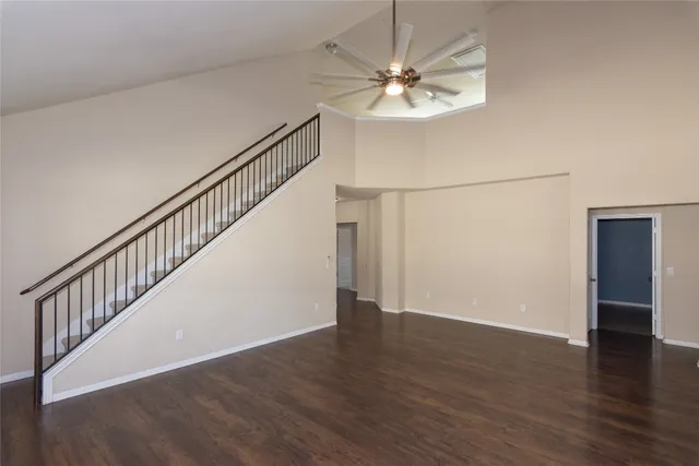 a view of an empty room with wooden floor and staircase