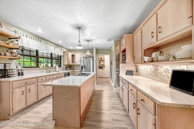 a large white kitchen with stainless steel appliances kitchen island granite countertop a lot of counter space and wooden floors