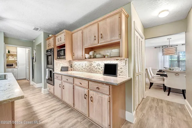 a kitchen with stainless steel appliances a stove a sink dishwasher a refrigerator and white cabinets with wooden floor