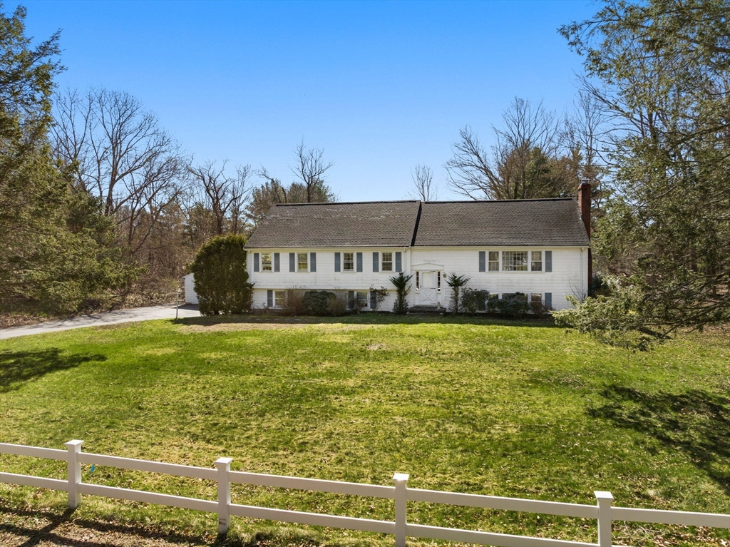 a front view of house with yard and trees in the background