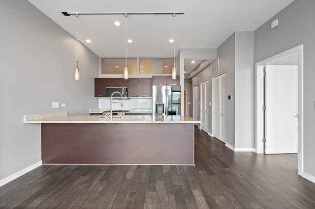 a large kitchen with stainless steel appliances granite countertop a large counter top a sink and a refrigerator