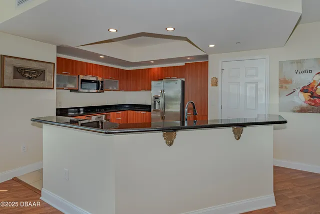 a kitchen with stainless steel appliances granite countertop a sink and a refrigerator