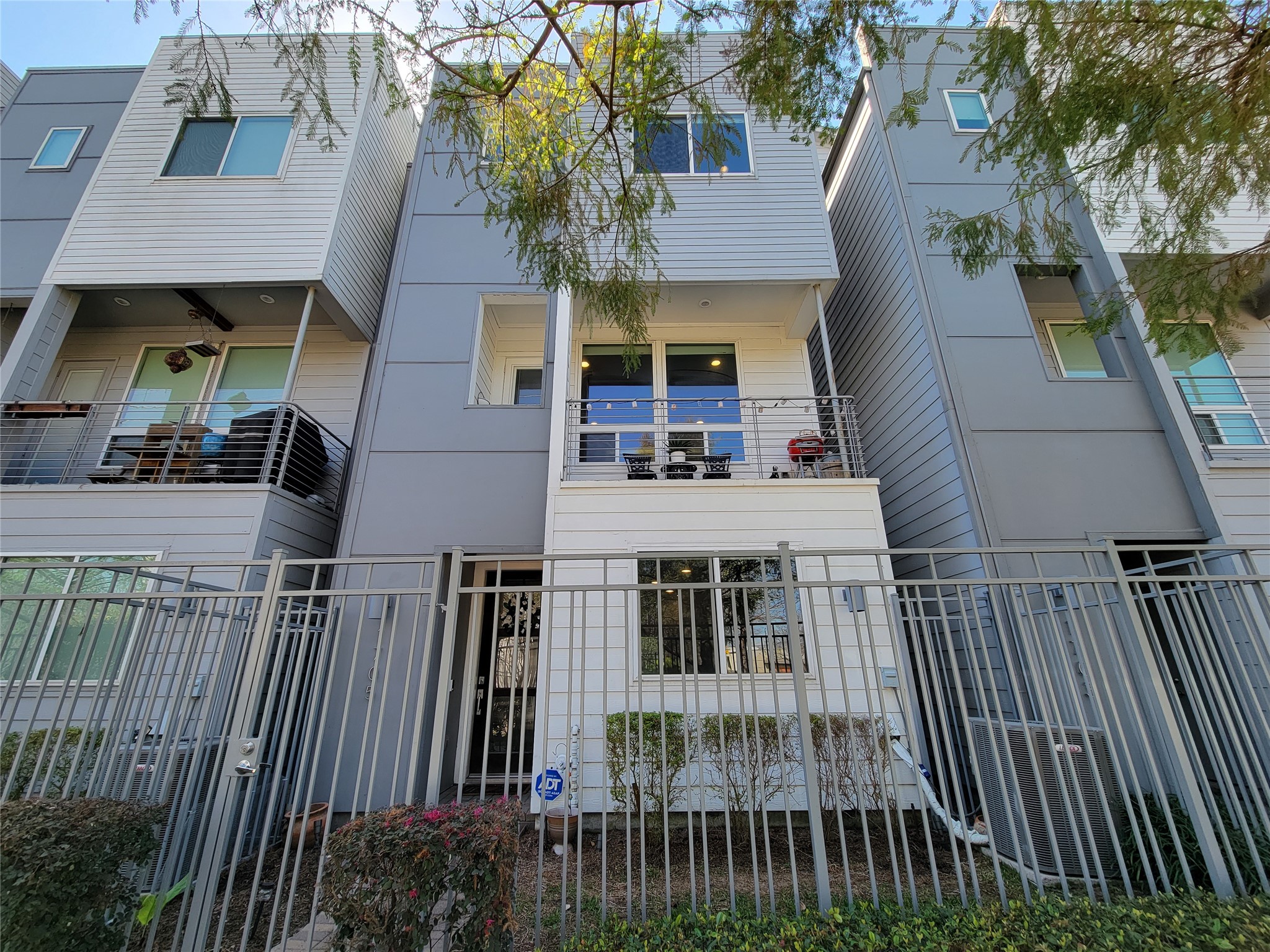 1705 Eado Point Lane Houston, TX 77003 - Photo 2 of 50 Modern three-story townhouse with a sleek design, featuring a balcony, large windows, and a secure front gate. Ideal for urban living.