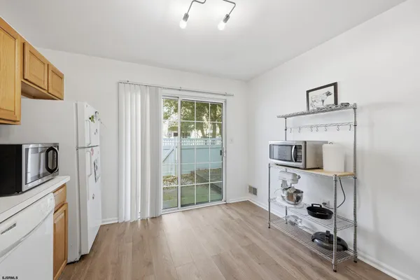 a view of a kitchen with wooden floor electronic appliances and windows