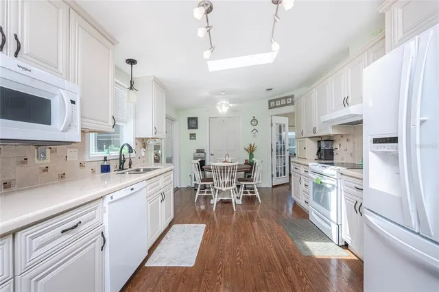 a kitchen with white cabinets appliances and wooden floor