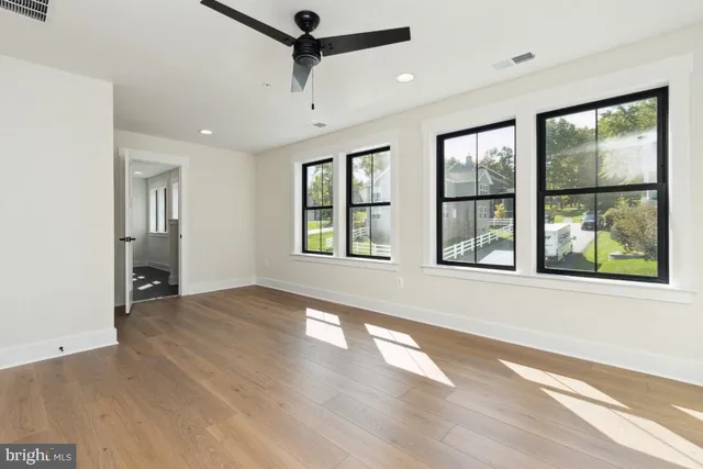 a view of an empty room with a window and wooden floor