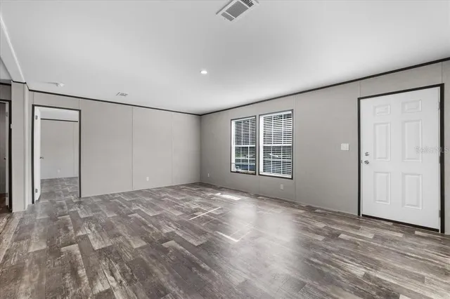 a view of an empty room with a window and wooden floor
