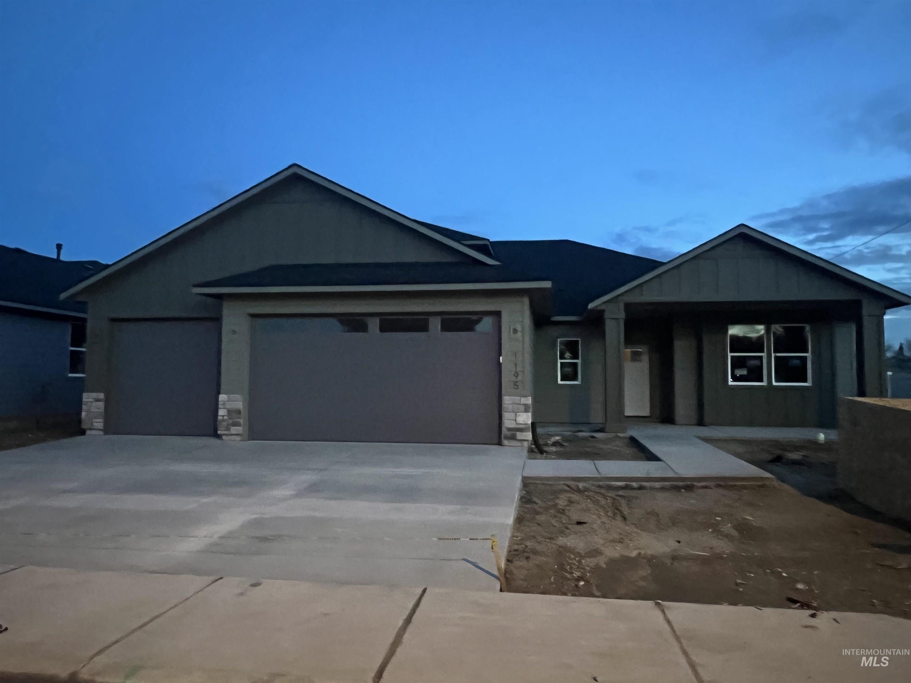 View of front of home with board and batten siding, stone siding, concrete driveway, and a garage