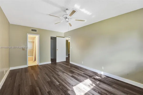an empty room with wooden floor chandelier fan and windows