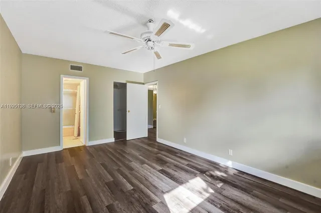 an empty room with wooden floor chandelier fan and windows