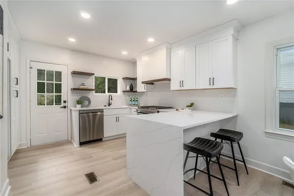 a kitchen with a sink a stove a refrigerator cabinets and a dining table