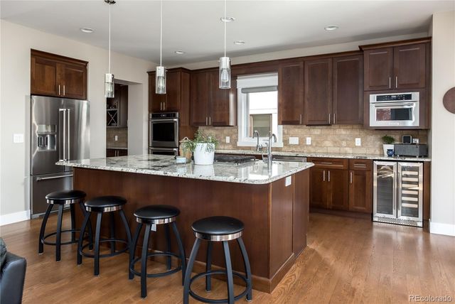 a kitchen with stainless steel appliances granite countertop a stove a sink dishwasher and a refrigerator with wooden cabinets