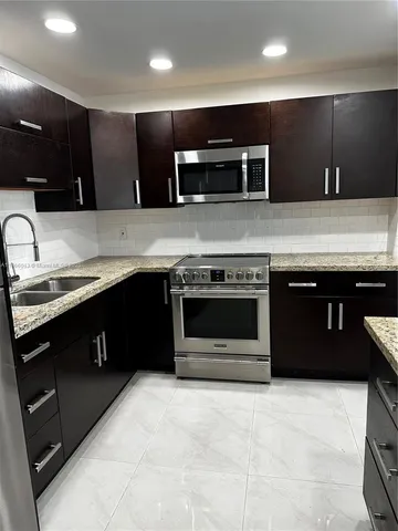 a kitchen with stainless steel appliances granite countertop a stove sink and cabinets