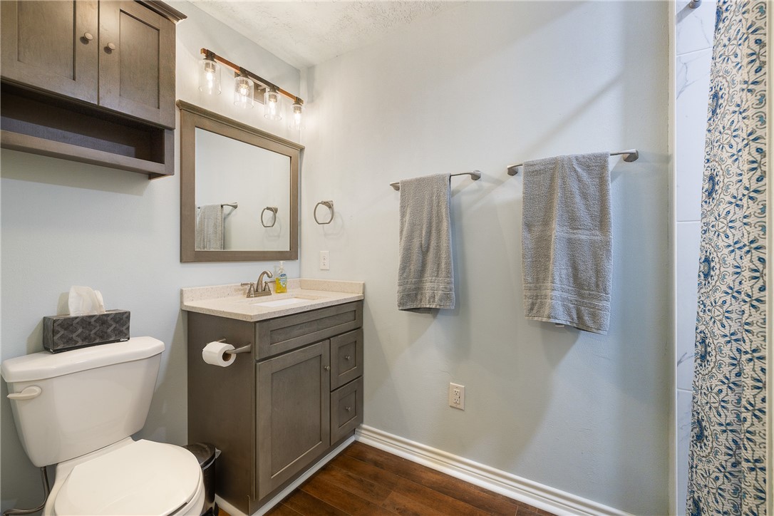 0 Clear Lake Road Bryan, TX 77808 - Photo 16 of 34 Bathroom featuring dark wood-type flooring, vanity, a shower with shower curtain, and a textured ceiling
