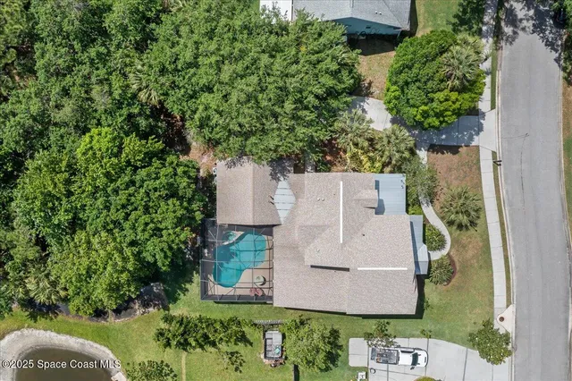 an aerial view of a house with a yard and trees all around