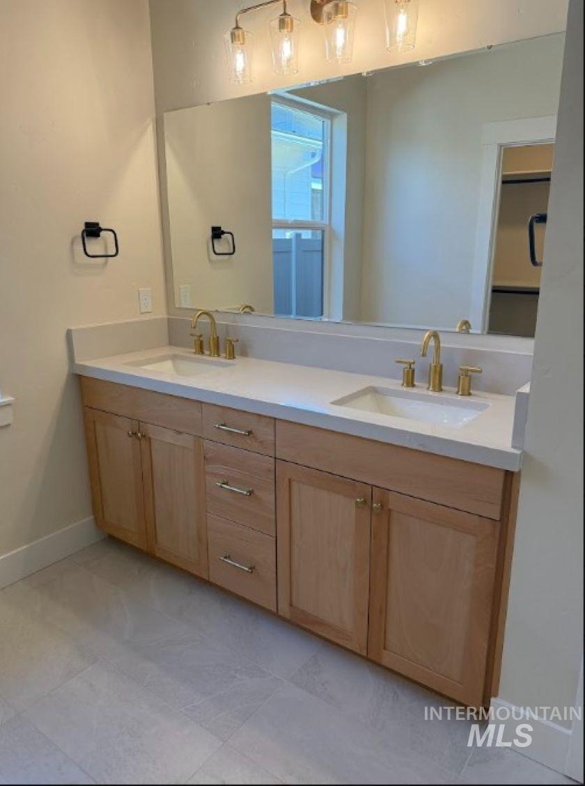 683 West Wrangler Street Meridian, ID 83646 - Photo 13 of 23 Double vanity featuring light wood-finish cabinetry, white countertops, and dual undermount sinks with brass fixtures