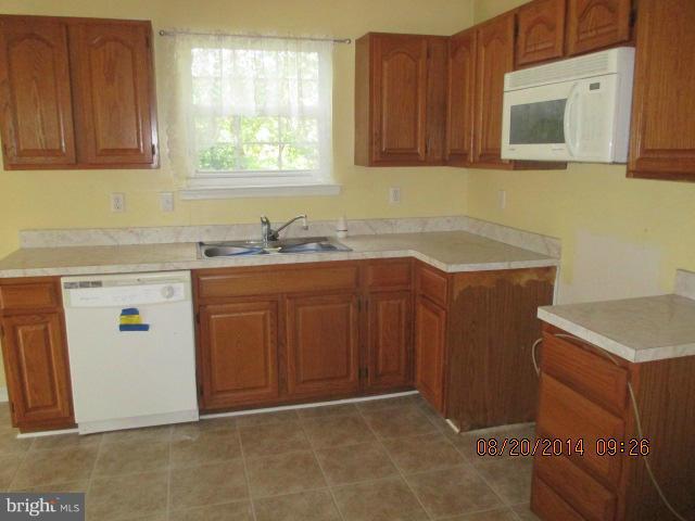743 Lazy River Road Lusby, MD 20657 - Photo 3 of 16 a kitchen with stainless steel appliances granite countertop wooden cabinets a sink and a stove