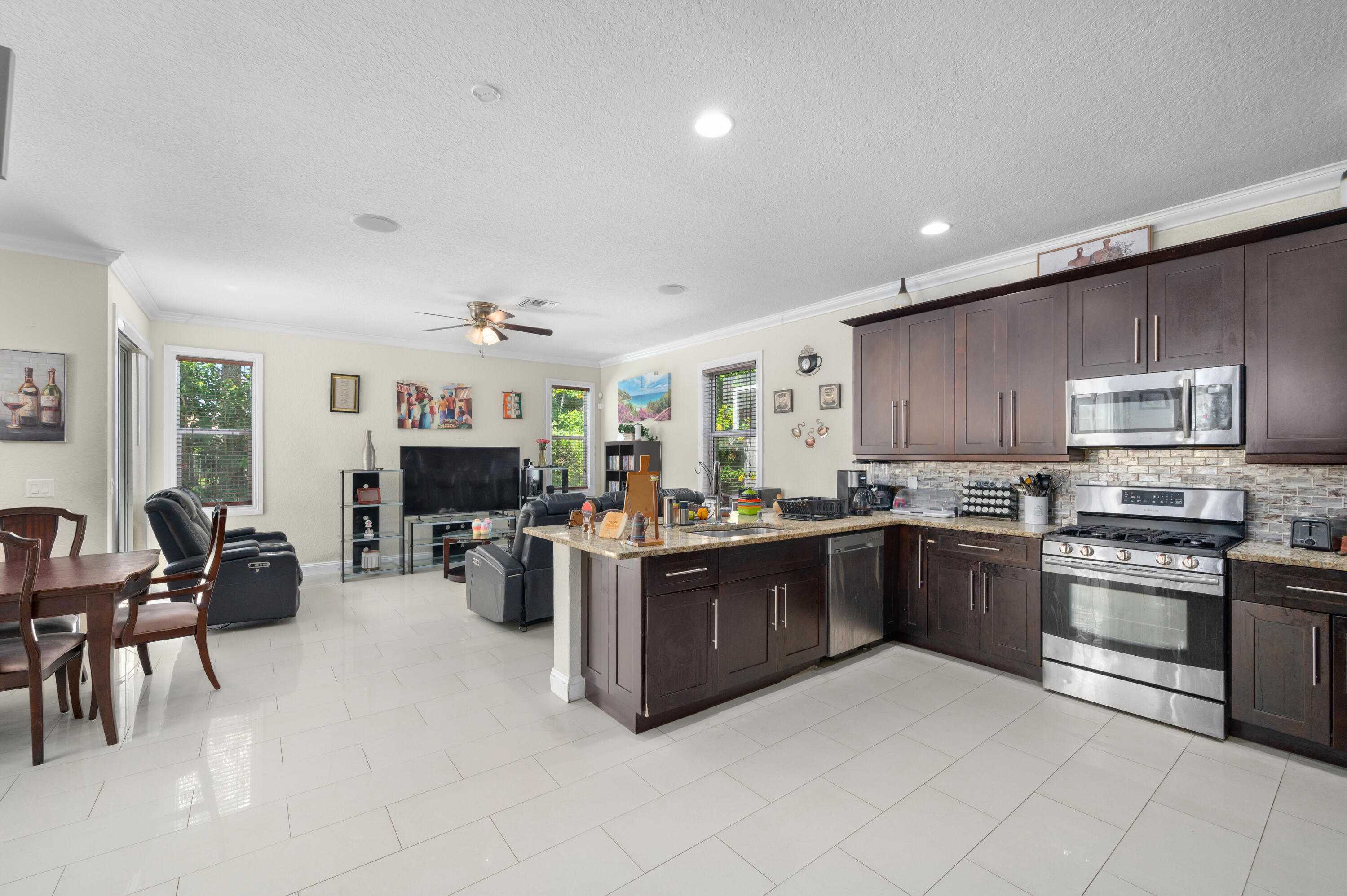 311 Berenger Walk Royal Palm Beach, FL 33414 - Photo 7 of 34 a kitchen with stainless steel appliances kitchen island granite countertop a stove top oven a sink dishwasher a dining table and chairs