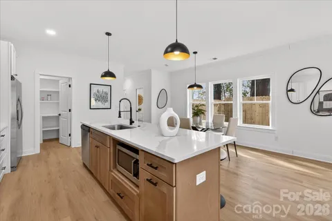 a kitchen with stainless steel appliances granite countertop a sink a stove and a wooden floors