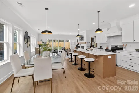 a kitchen with stainless steel appliances kitchen island granite countertop a table chairs and a wooden floor