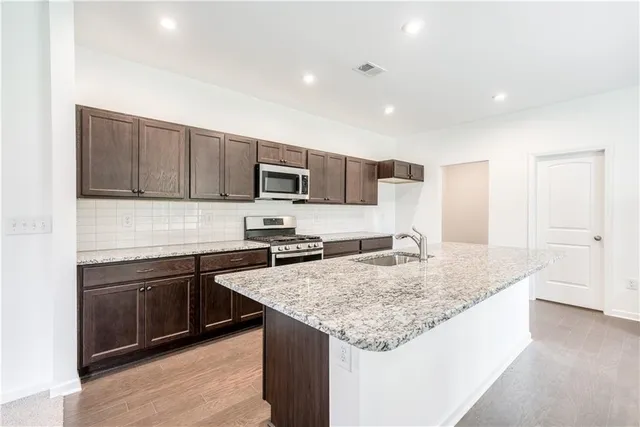 a kitchen with stainless steel appliances granite countertop a sink stove and refrigerator