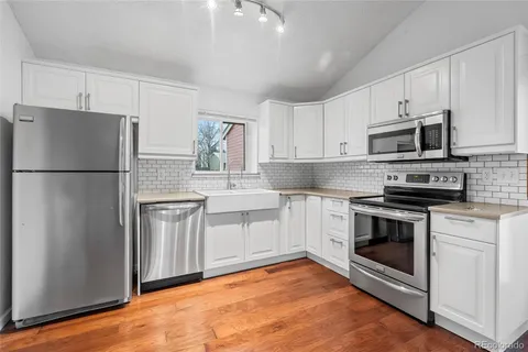a kitchen with cabinets stainless steel appliances and wooden floor