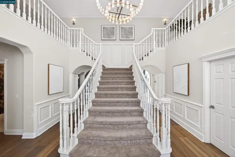a view of staircase with lots of frames on wall and wooden floor