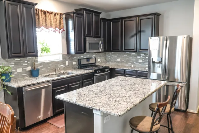 a kitchen with kitchen island granite countertop a sink stove and refrigerator