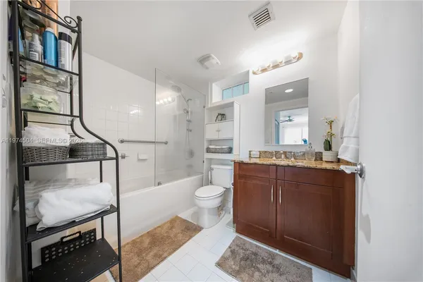 a spacious bathroom with a granite countertop sink a toilet a mirror and shower