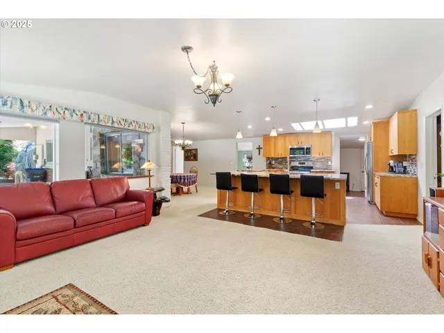 a living room with furniture kitchen view and a chandelier